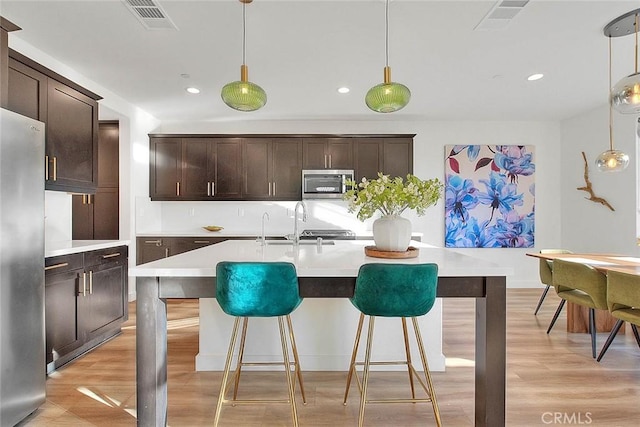 kitchen featuring pendant lighting, dark brown cabinets, and stainless steel appliances