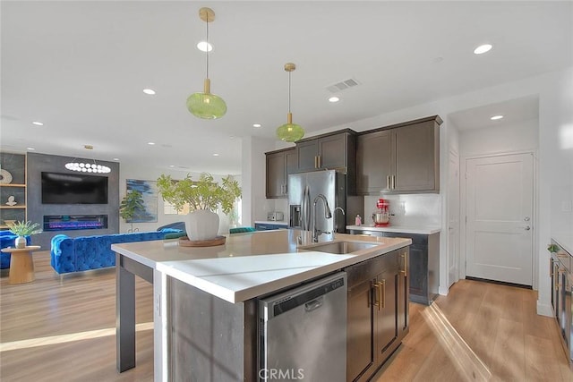 kitchen featuring sink, decorative light fixtures, dark brown cabinets, an island with sink, and stainless steel appliances