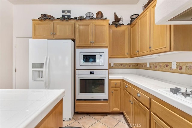 kitchen featuring white appliances, tile countertops, and light tile patterned floors