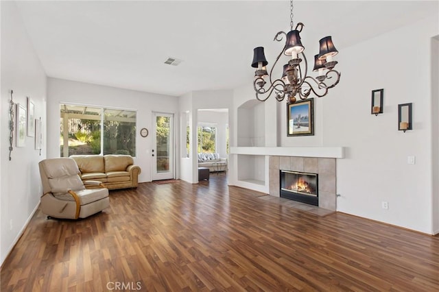 living room featuring dark wood-type flooring, a chandelier, and a fireplace