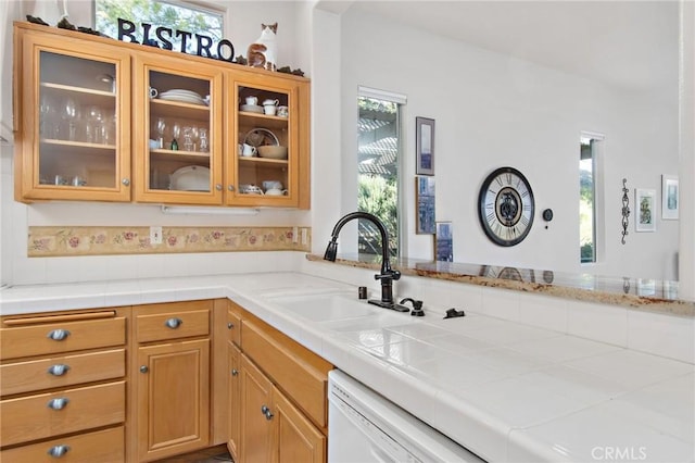 bar featuring dishwasher, sink, and tile countertops