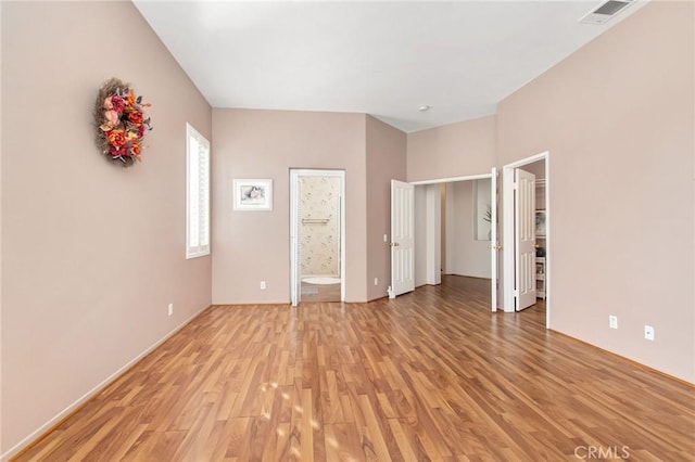 unfurnished bedroom with a walk in closet, light hardwood / wood-style floors, and ensuite bath