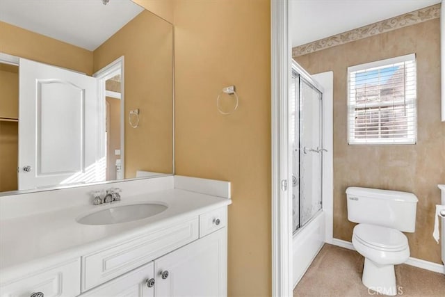 full bathroom with enclosed tub / shower combo, vanity, and toilet