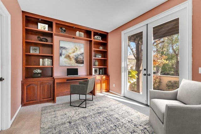 office area with built in shelves, light colored carpet, and french doors