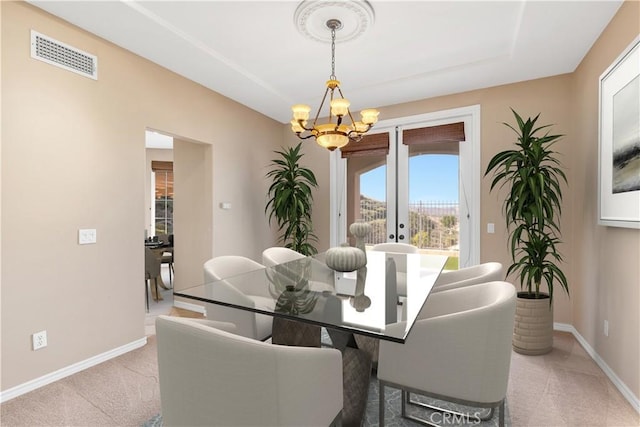 carpeted dining space featuring a notable chandelier and french doors