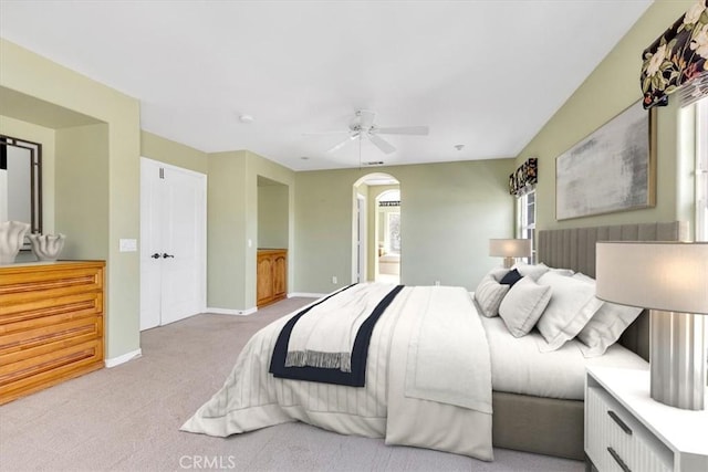 bedroom featuring light carpet, connected bathroom, and ceiling fan