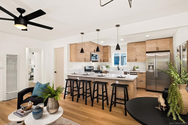 kitchen with ceiling fan, appliances with stainless steel finishes, decorative light fixtures, and light wood-type flooring