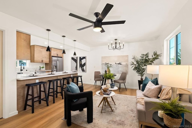 living room with ceiling fan with notable chandelier and light wood-type flooring