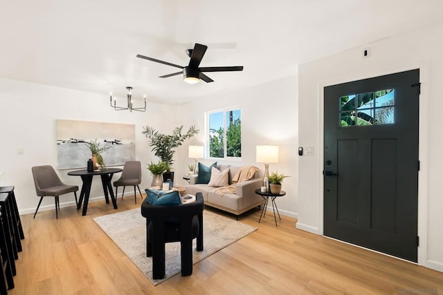 living room with ceiling fan with notable chandelier and light wood-type flooring