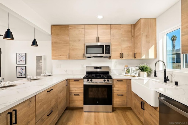 kitchen featuring pendant lighting, sink, appliances with stainless steel finishes, light stone counters, and light brown cabinets