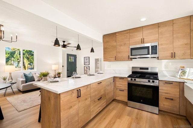 kitchen featuring a kitchen bar, light wood-type flooring, kitchen peninsula, and appliances with stainless steel finishes