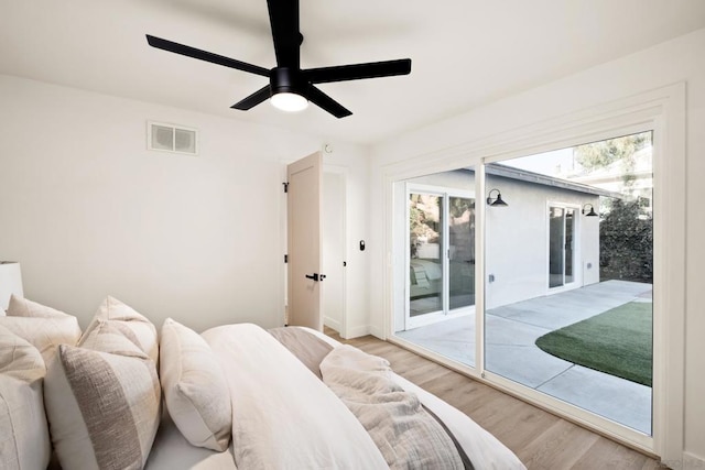 bedroom with multiple windows, wood-type flooring, access to exterior, and ceiling fan