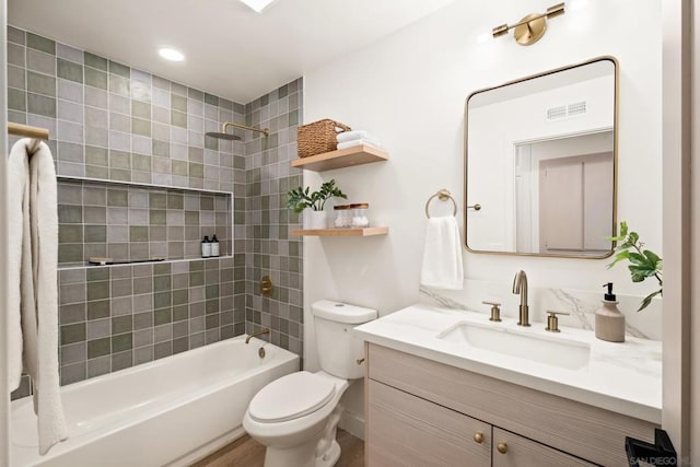 full bathroom featuring vanity, tiled shower / bath, and toilet