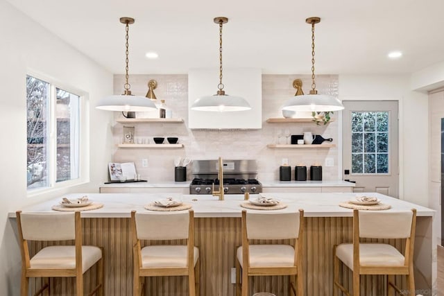 kitchen featuring pendant lighting, a breakfast bar area, range, and backsplash