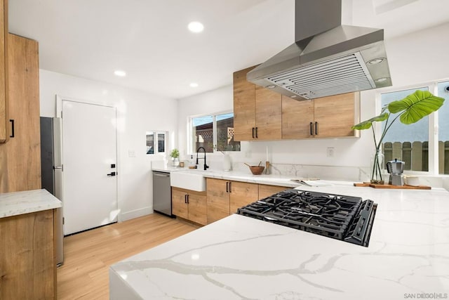 kitchen featuring sink, light hardwood / wood-style flooring, dishwasher, light stone countertops, and island exhaust hood