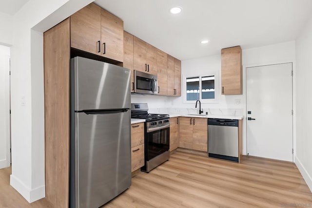 kitchen with light brown cabinetry, sink, light hardwood / wood-style flooring, and appliances with stainless steel finishes