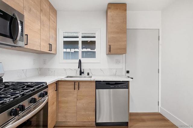 kitchen featuring light stone counters, appliances with stainless steel finishes, sink, and light brown cabinets