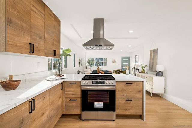 kitchen with range hood, light stone counters, light hardwood / wood-style floors, stainless steel range oven, and kitchen peninsula