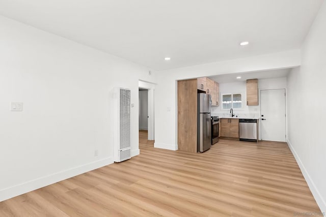 kitchen with appliances with stainless steel finishes, sink, and light wood-type flooring