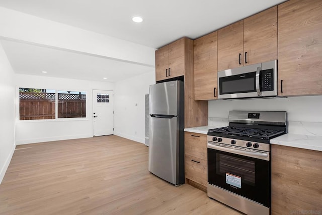 kitchen with light hardwood / wood-style flooring and appliances with stainless steel finishes