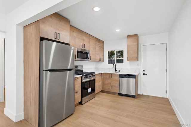 kitchen featuring stainless steel appliances, sink, and light hardwood / wood-style flooring