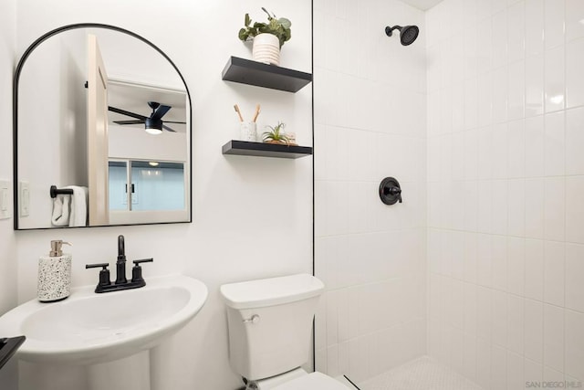 bathroom with sink, a tile shower, ceiling fan, and toilet