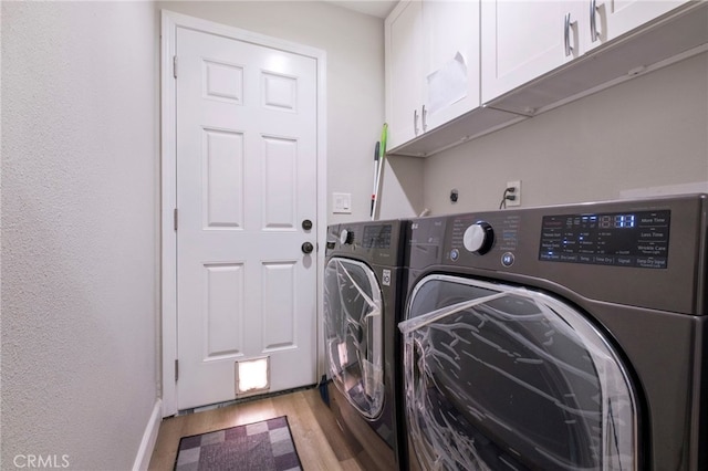 laundry room featuring cabinets, washer and dryer, and light wood-type flooring