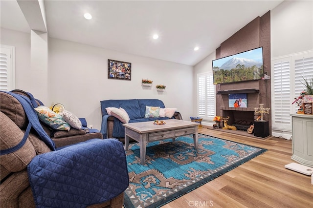 living room with lofted ceiling, light hardwood / wood-style flooring, and a large fireplace