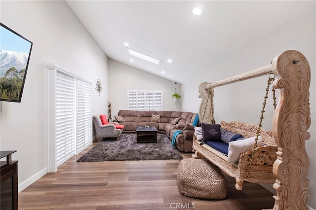 living room featuring wood-type flooring, high vaulted ceiling, and a skylight