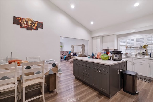 kitchen with a center island, white cabinets, high vaulted ceiling, and light hardwood / wood-style flooring