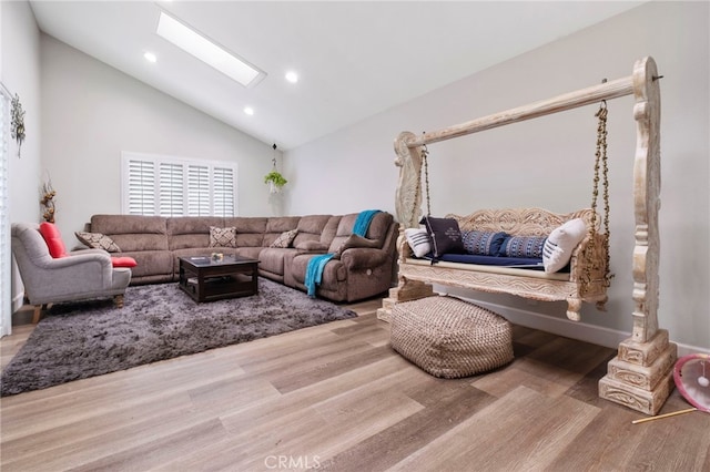 living room with high vaulted ceiling, light wood-type flooring, and a skylight