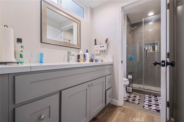 bathroom with wood-type flooring, toilet, a shower with door, and vanity