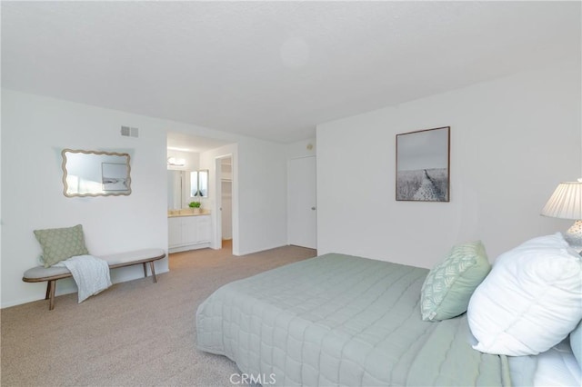 bedroom featuring ensuite bath and light carpet