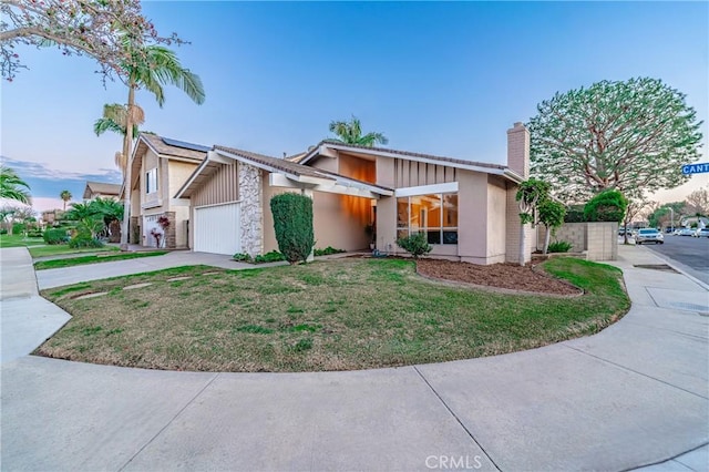 view of front of property with a garage and a lawn