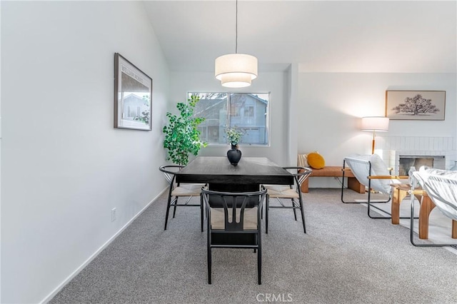 carpeted dining area with lofted ceiling and a fireplace