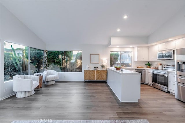 kitchen featuring appliances with stainless steel finishes, kitchen peninsula, hardwood / wood-style floors, and white cabinets