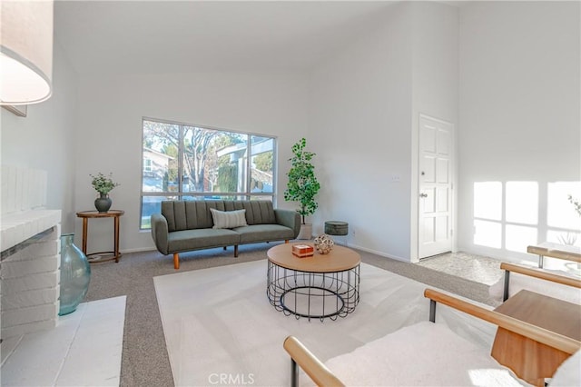 carpeted living room featuring a fireplace and high vaulted ceiling