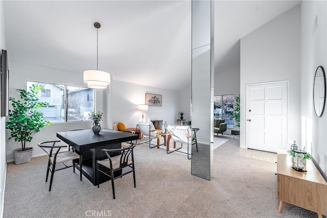 carpeted dining area featuring high vaulted ceiling