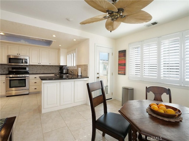 kitchen featuring light tile patterned flooring, sink, tasteful backsplash, appliances with stainless steel finishes, and kitchen peninsula