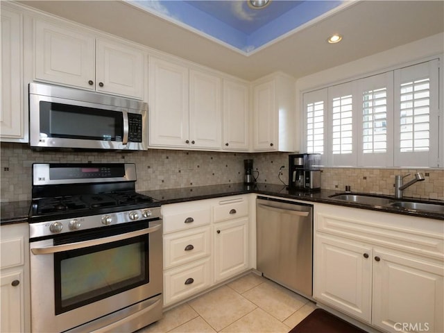 kitchen featuring sink, white cabinetry, backsplash, stainless steel appliances, and light tile patterned flooring