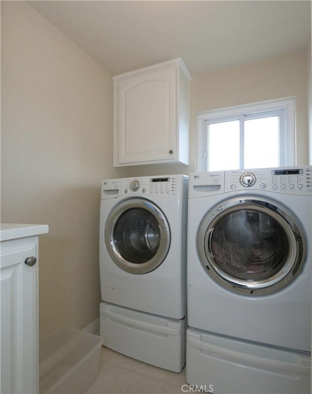 laundry area featuring cabinets, washer and dryer, and light tile patterned floors