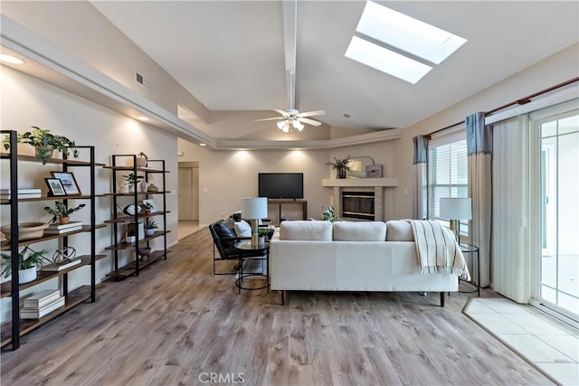 living room with hardwood / wood-style flooring, ceiling fan, a fireplace, and vaulted ceiling