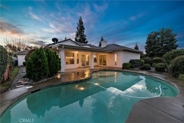 pool at dusk featuring a patio