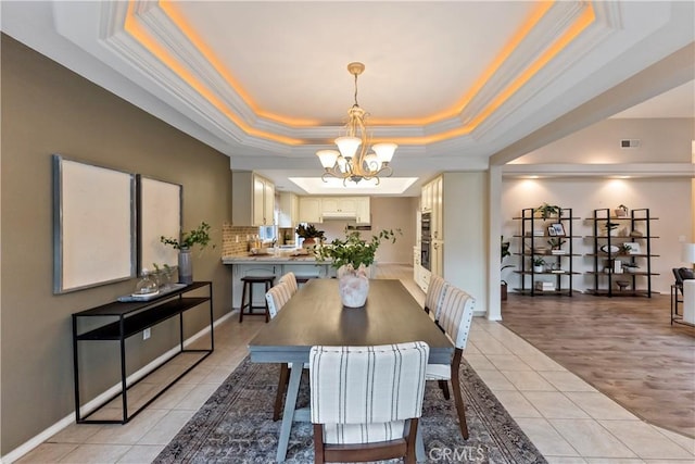 dining room with an inviting chandelier, light tile patterned floors, a tray ceiling, and ornamental molding