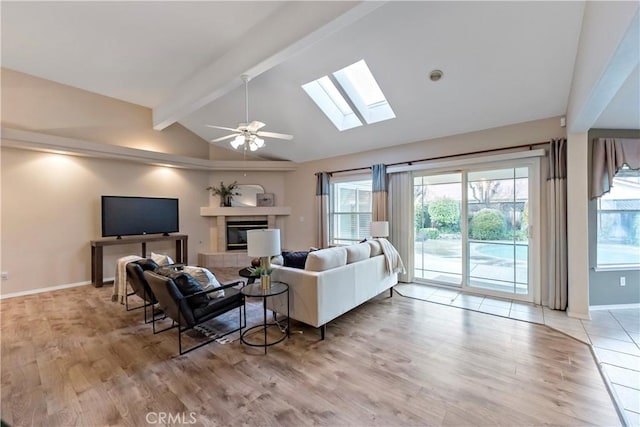 living room with lofted ceiling with beams, ceiling fan, a fireplace, and light hardwood / wood-style floors