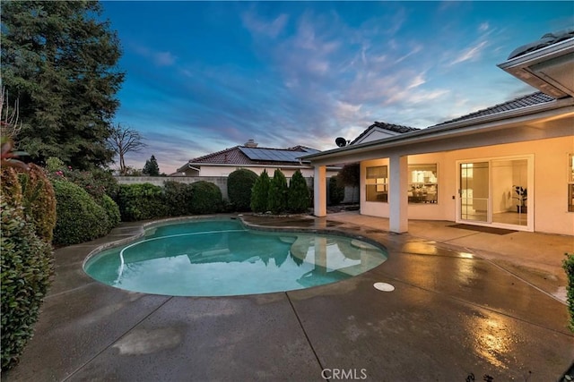 pool at dusk featuring a patio area