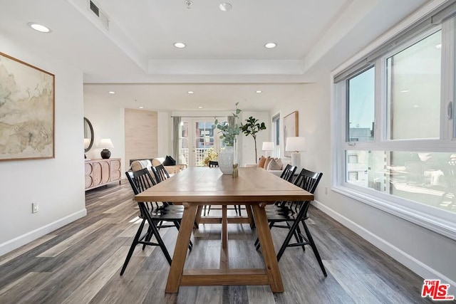 dining area featuring dark hardwood / wood-style flooring and a tray ceiling