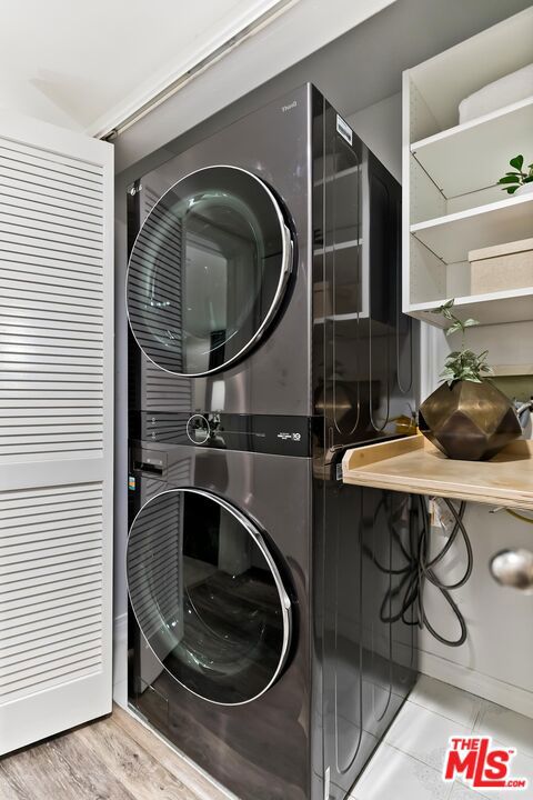 laundry area featuring stacked washing maching and dryer and light hardwood / wood-style floors