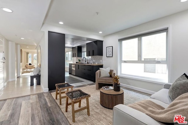 living room with a healthy amount of sunlight, sink, and light hardwood / wood-style floors