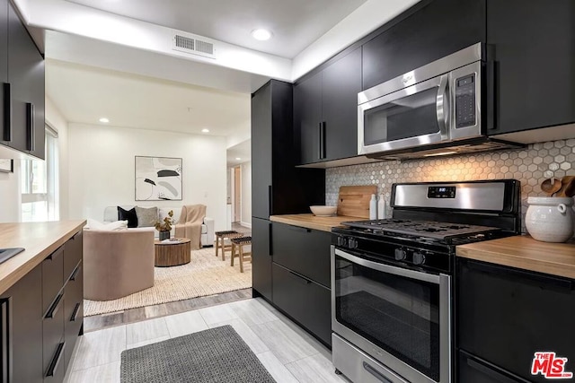 kitchen featuring wood counters, decorative backsplash, and appliances with stainless steel finishes